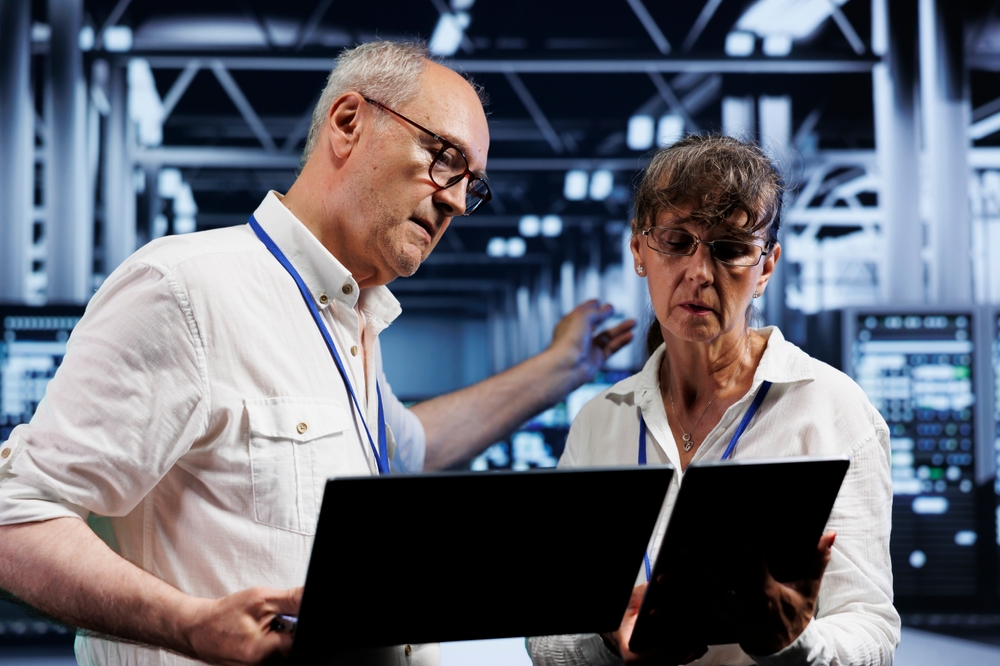 Business analysts examining data dashboards on computers to support simulation modeling and operational planning.