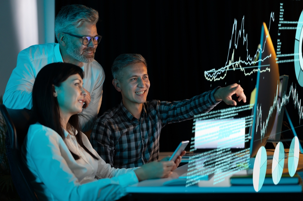 Team of professionals collaborating around a computer while reviewing results from simulation modeling.