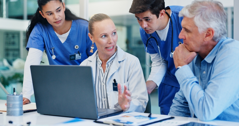 Healthcare team meeting around a screen to plan operations with digital twins in healthcare
