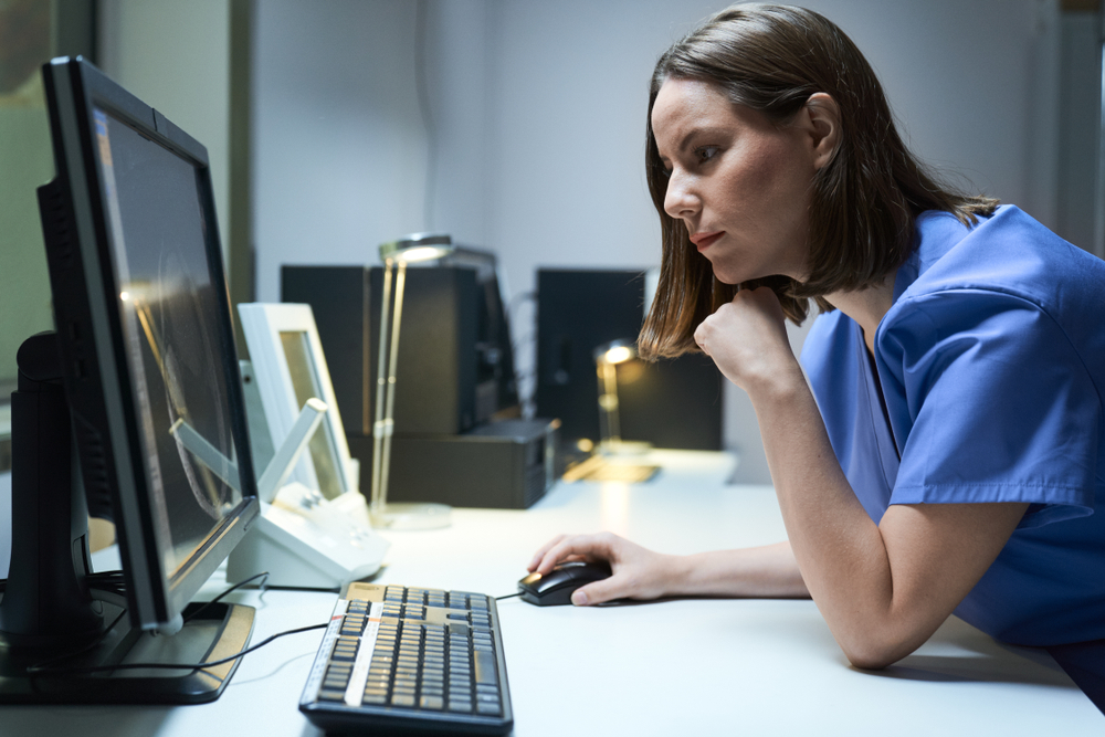 Nurse reviewing patient flow data on a computer, showing how digital twins in healthcare support hospital planning
