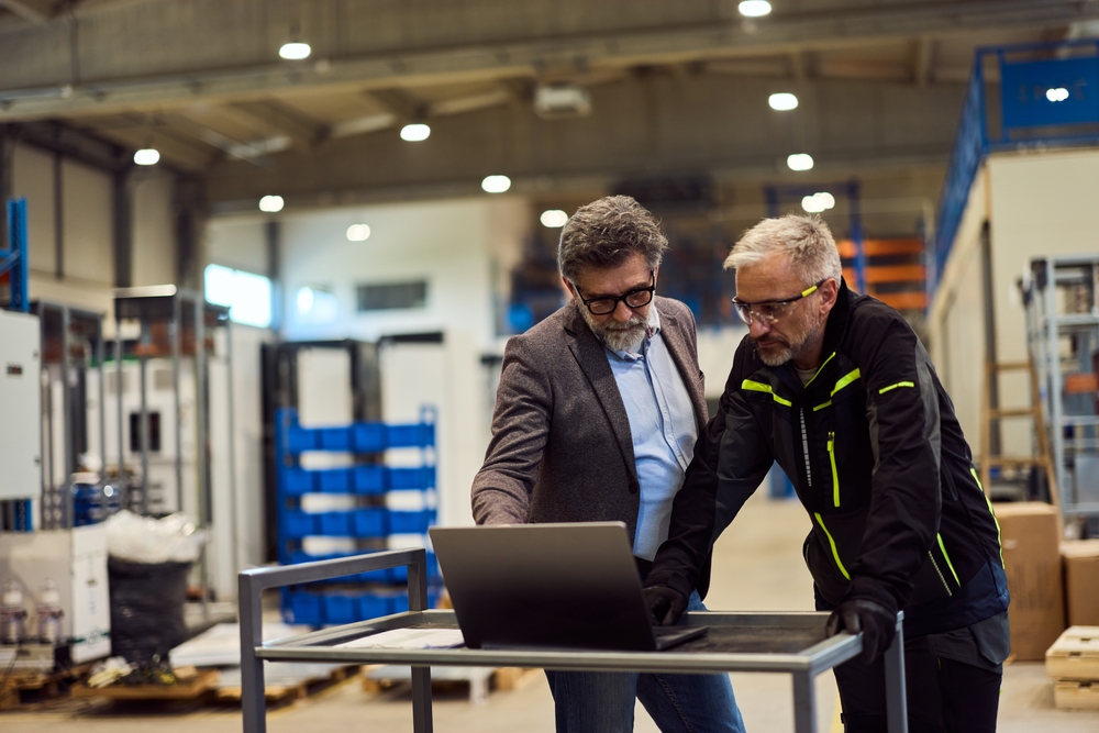 Managers planning warehouse optimization for labor and dock schedules around a laptop